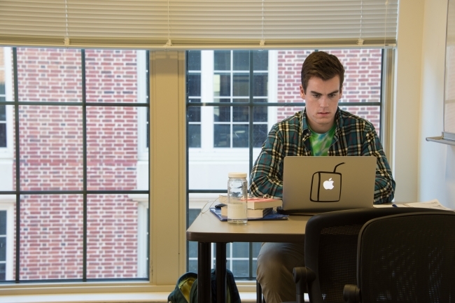 Study room of dorms where student does homework on his laptop